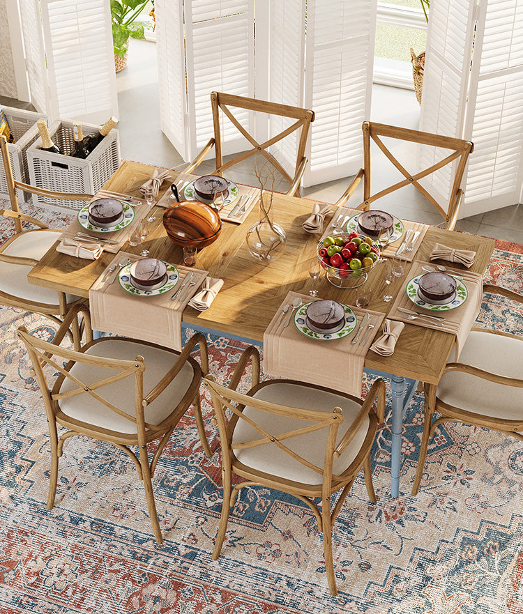 A spacious dining area with natural lighting features a large, intricate washable rug with a blend of blue, red, and beige patterns. 