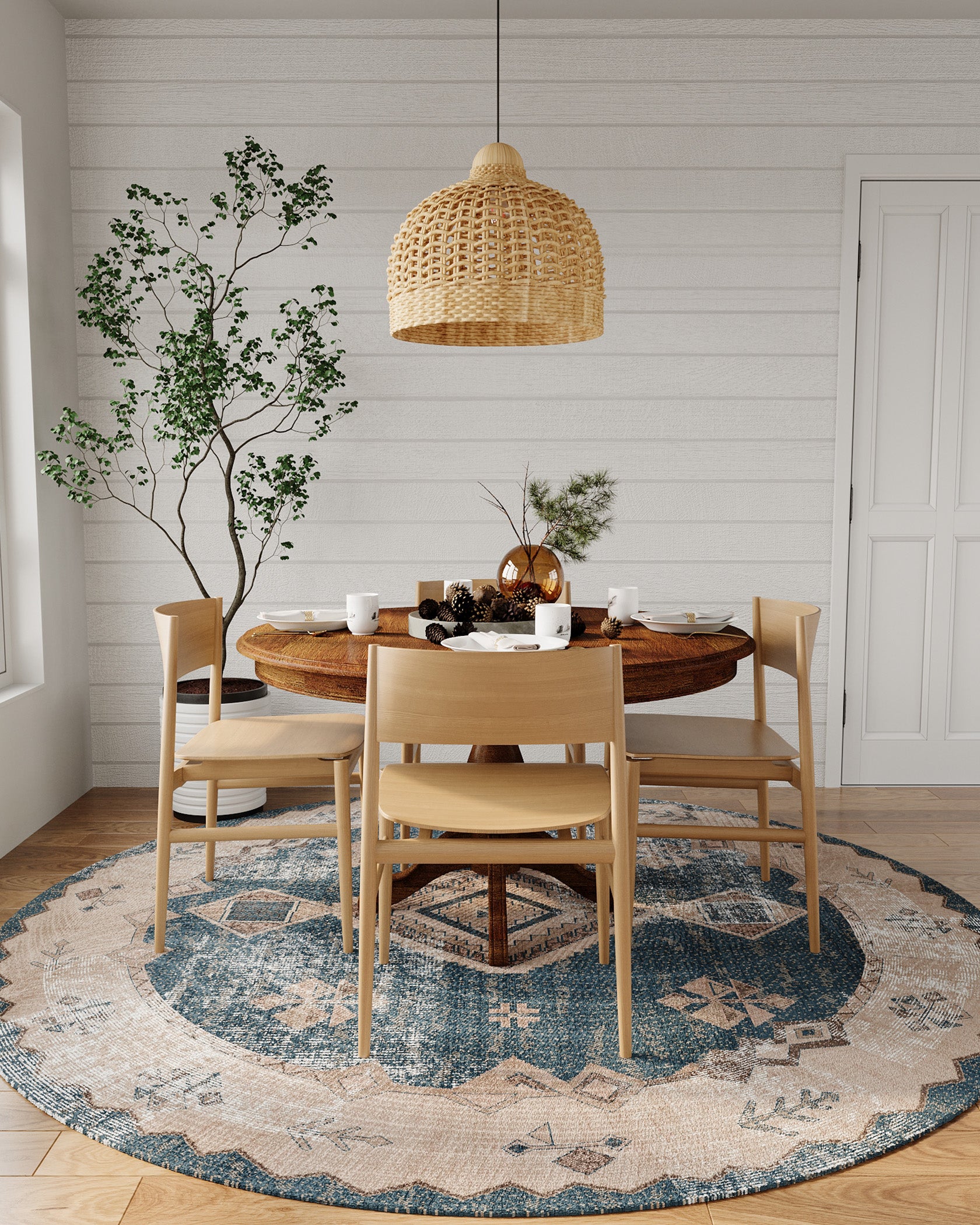 A serene dining area illuminated by a woven pendant light showcases a round washable rug with shades of blue, beige, and white, featuring geometric patterns. 