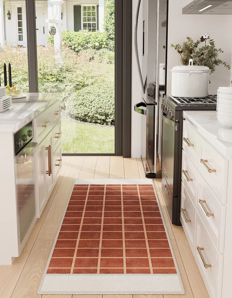 Durable 75 x 215 washable runner rug in red with grid pattern, enhancing a bright modern kitchen with white cabinetry and garden view